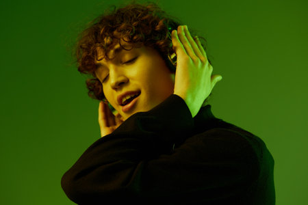Man party with headphones listening to music, dancing and singing, DJ teenager happiness and smile, hipster lifestyle, portrait green background mixed neon light, copy spaceの写真素材