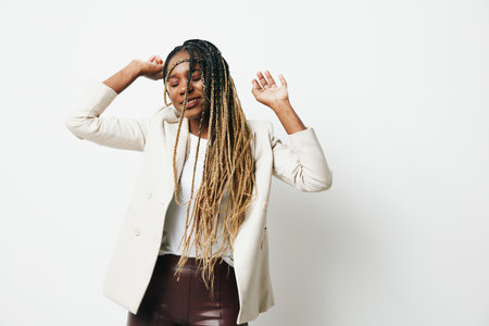 Portrait african american business woman happiness and smile dance, business clothes and jacket with afro pigtails smile. White background. Soft warm colors.の写真素材