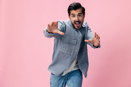 Fashion brunette man with beard happiness open mouth jumping and running with his arms spread on a pink background in a white T-shirt and jeans smile and joyful emotion on his face, copy spaceの写真素材