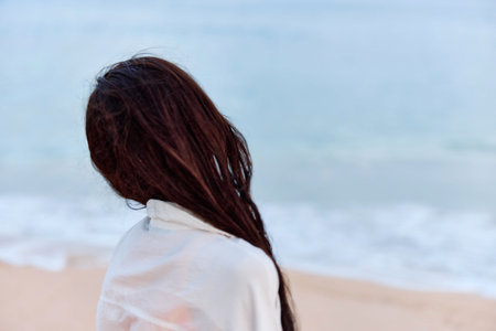 Portrait of a woman smile with teeth in a yellow tank top and white beach shirt with wet hair after swimming on the ocean beach sunset lightの写真素材