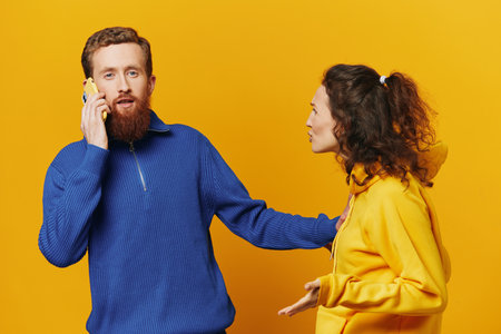 Man and woman couple with phone in hand call talking on the phone, on a yellow background, symbols...