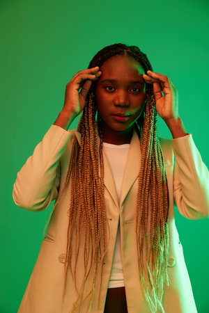 African american woman portrait business smile on green background in neon light, color mixed light, bright colors. Beauty African American woman with pigtails emotions.の写真素材