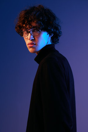 Male fashion portrait in black clothes model poses in glasses, hipster lifestyle, portrait blue...
