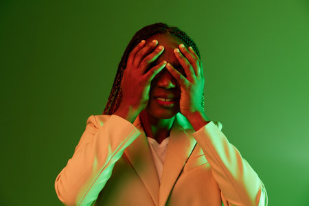 African american woman portrait business smile on green background in neon light, color mixed light, bright colors. Beauty African American woman with pigtails emotions.の写真素材