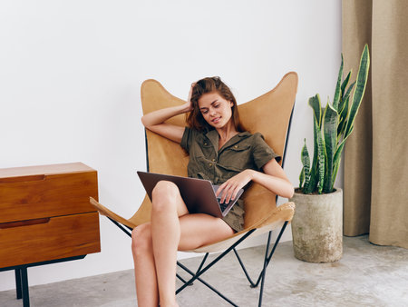 Woman freelancer sitting in chair with laptop work at home smile, modern stylish interior Scandinavian lifestyle, copy space.の写真素材