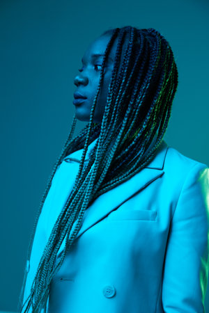 African american woman portrait business smile and fashion wearing glasses on blue background in neon light, color mixed light, bright color dancing, futuristic party. Flying pigtails hair emotions.の写真素材