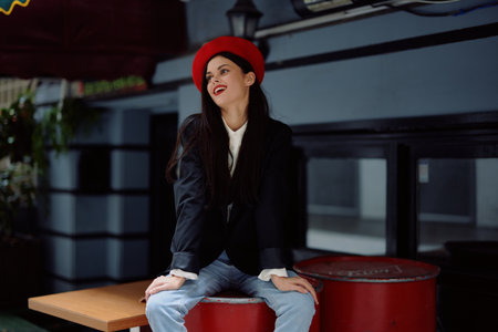 Woman sitting outside a cafe and bar on a city street, stylish fashion image of clothes, vacation and travel, city walk.の写真素材