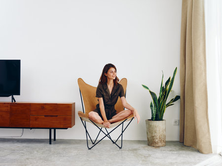 Woman sitting in a leather armchair near the window smiling , modern stylish interior Scandinavian lifestyle, copy space.の写真素材