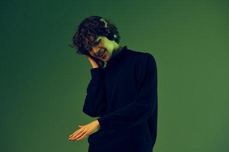 Male teenager in headphones listening to music, dancing and singing with his eyes closed, DJ...