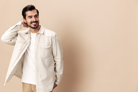 Portrait of a stylish man smile with teeth happiness opened his mouth in surprise on a beige background in a white t-shirt looks at the camera, fashionable clothing style, copy space, space for textの写真素材