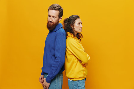 Man and woman couple smiling cheerfully and crooked with glasses, on yellow background, symbols signs and hand gestures, family shoot, newlyweds.の写真素材