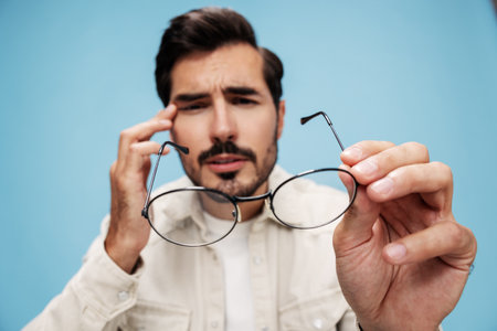 Close-up portrait of a brunette man looking through glasses that he holds in his hands, eye...