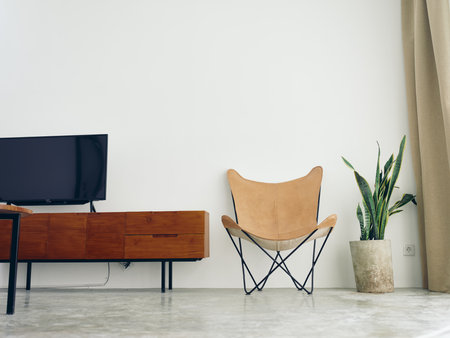 Stylish leather chair chair in a modern interior with white walls and concrete floor, wooden elements, natural daylight from the window.の写真素材