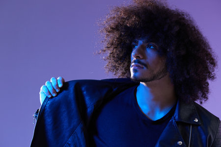Portrait of fashion man with curly hair on blue background multinational, colored light, black...