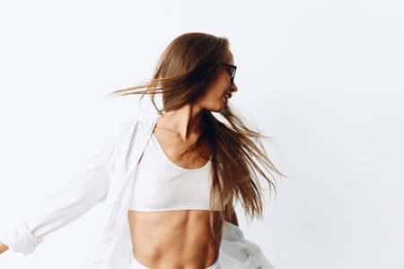 Beautiful female fashion model with tanned skin and long natural flowing hair posing on a white background with sunglasses for visionの写真素材