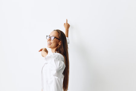 Happy woman with tanned skin having fun at home in a white top and white shirt with glasses against a white wall, lifestyleの写真素材