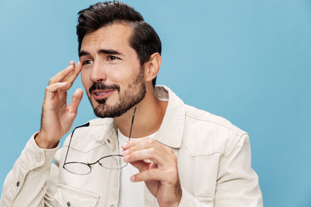 Close-up portrait of a man looking through glasses that he holds in his hands, dioptric lenses,...