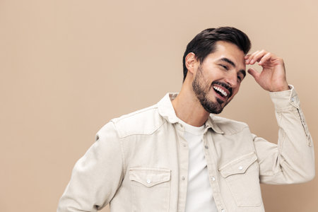 Portrait of a stylish man smile closeup on a beige background in a white t-shirt, fashionable clothing style, copy spaceの写真素材