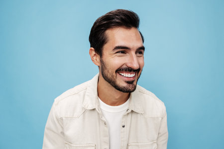 Close-up portrait of a brunette man looking through glasses that he holds in his hands, eye problems, glasses for vision farsightedness and nearsightedness, on a blue background, copy spaceの写真素材