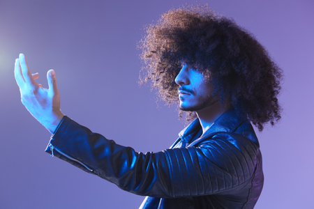 Portrait of fashion man with curly hair on blue background multinational, colored light, black...