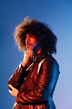 Portrait of a stylish man with curly hair in smoke on a blue background multinational, color light, trendy, modern concept.の写真素材