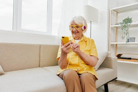 Happy elderly woman looking into phone video call smile, technology for communication, bright modern interior, lifestyle online communication.の写真素材
