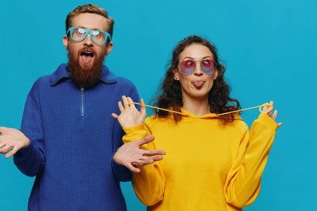 A woman and a man fun couple cranking and showing signs with their hands smiling cheerfully, on a blue background, The concept of a real relationship in a family.の写真素材