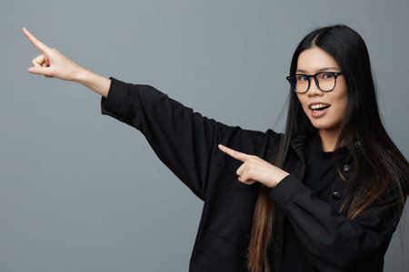 Woman portrait pointing asian student fashion smile business background cute studio beautiful glasses fingerの写真素材