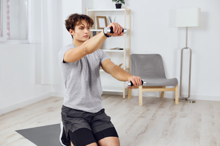 exercising man lifestyle sport training gray activity home indoor dumbbells healthの写真素材