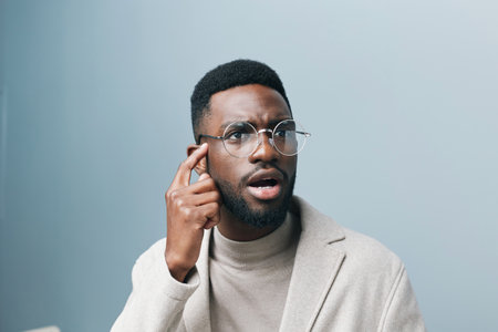 Cheerful african man wearing glasses jean jacket having white snow smile pointing fingers aside at copy space for your text advertisement, advertise teeth whitening or eyewear store good offer conceptの写真素材