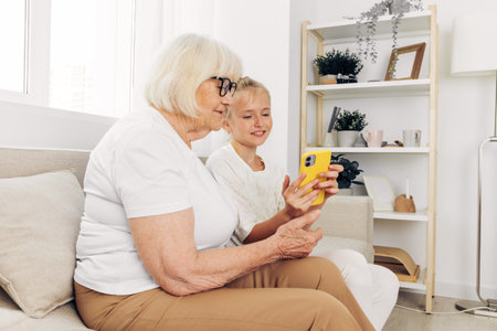 Grandmother child smiling phone hugging family bonding granddaughter togetherness selfieの写真素材