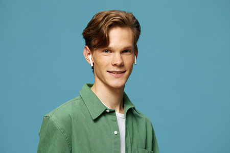 Young man smiling in green shirt against blue background.