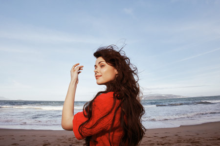 Smiling Woman Enjoying Freedom and Joy at the Beach: A Portrait of a Happy, Young Lady with Red Clothesの写真素材