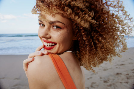 Beach Wanderlust: Happy Woman with Smiling Open Mouth, Backpack, and Curly Hair Embracing Freedom in Wide Angle Lens Portraitの写真素材