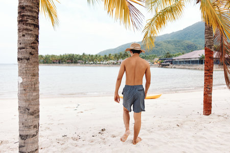 Happy Asian Man Enjoying Kayaking Adventure on Tropical Beachの写真素材