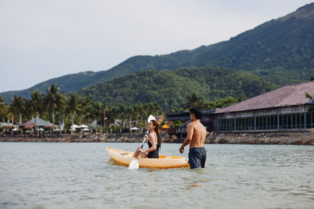 Kayaking Harmony: A Joyful Asian Couple Paddling in the Serene Tropical Watersの写真素材