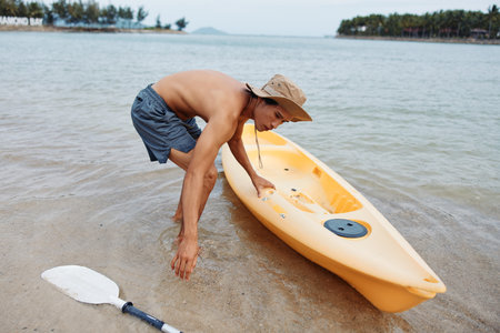 Summer Fun: An Asian Man Experiencing the Joy of Kayaking on a Tropical Beachの写真素材