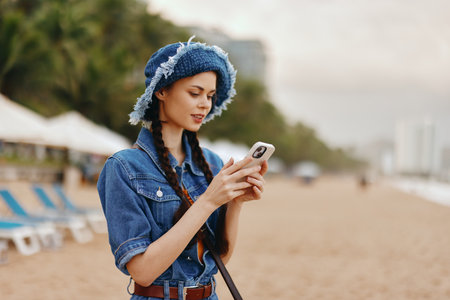 Beauty in Nature: Young Female Enjoying Summer Vacation, Using Smartphone on the Beachの写真素材