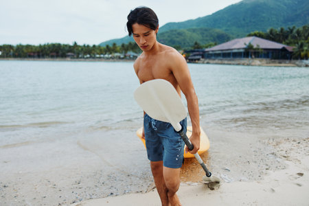 Kayak Fun in the Sun: Happy Asian Man Enjoying Active Summer Vacation on Tropical Beach