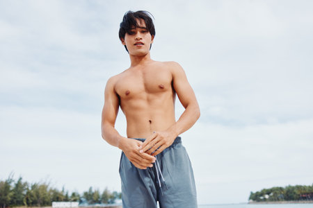 Muscular Asian Man Running on the Beach: A Portrait of Strength, Freedom, and Healthy Lifestyleの写真素材