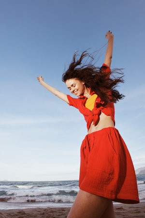 Smiling Woman Dancing with Joy on a Sunny Beach, Embracing the Freedom of Fun in the Summer Seaの写真素材