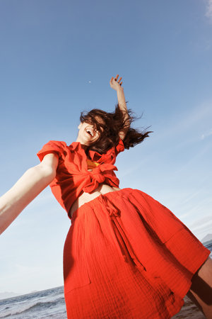 Joyful Embrace of Summer: Smiling Woman Dancing with Freedom and Happiness on the Beautiful Beachの写真素材