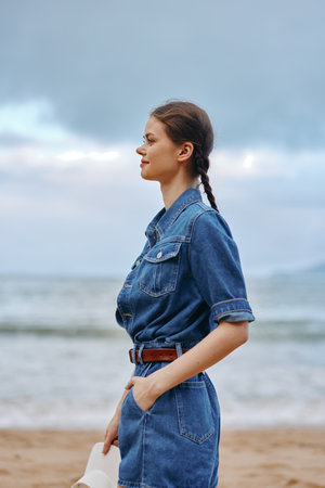 Serene Solitude: A Pretty Young Caucasian Woman Sitting Alone on a Calm Beach, Posing Against the Stunning Sunset over the Ocean, Embracing the Feeling of Freedom and Serenity in her Sad yet Glamorous Styleの写真素材