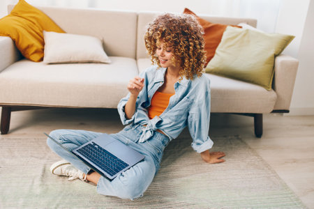 Smiling woman using laptop in cozy living roomの写真素材