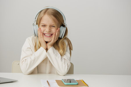Smiling girl learning elearning at home with a laptop a beautiful Caucasian schoolgirl sitting at a table, typing and studying online She looks happy and engaged, surrounded by notebooks and books Theの写真素材