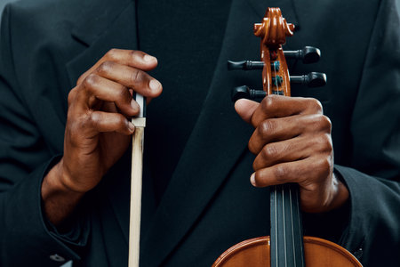 Close up of hands holding the bow of a violin, capturing the delicate touch and artistry of playing musicの写真素材