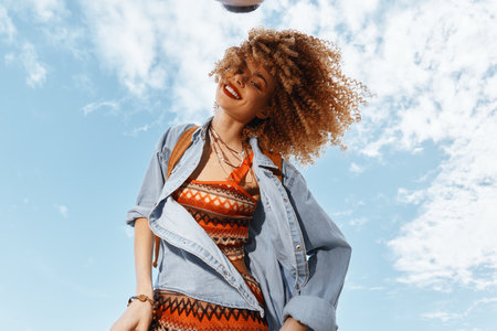 Smiling Woman Dancing on Beach, Embracing Freedom and Joy in a Curly-Haired Hippie Fashion