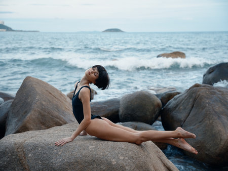 Summer Sensuality: Beautiful Woman in Sexy Swimwear Posing on a Rock by the Ocean.の写真素材