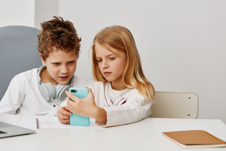 Happy Caucasian siblings using laptops for online learning and studying together at home