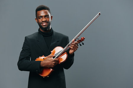 African American man in elegant suit holding violin on gray background for music and concert conceptの写真素材